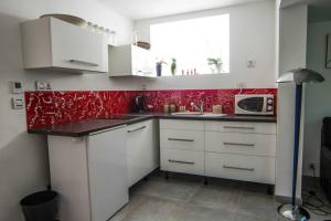 a kitchen with white cabinets and red wallpaper at Appartement avec jardin intérieur 4 pers centre ville in Nemours
