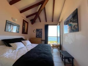 ein Schlafzimmer mit einem Bett und einem großen Fenster in der Unterkunft Maison de Lou in Porticcio