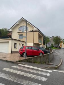 a red car parked in front of a house at Apartma Azurre in Postojna