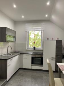 a kitchen with white cabinets and a sink and a window at Apartma Azurre in Postojna