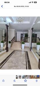 a large room with a staircase and a hallway with columns at Уютная квартира на набережной! in Astana