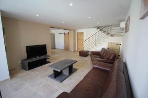 a living room with a couch and a tv at Maison de village 150 M2 au calme climatisée, piscine in Rasteau
