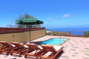 - un groupe de chaises et un parasol à côté de la piscine dans l'établissement Casa Florita, à Puntagorda