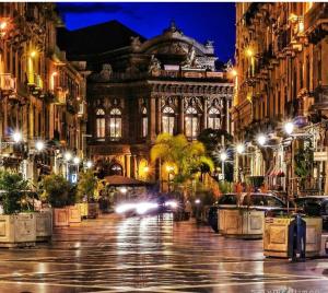 een stadsstraat 's nachts met een groot gebouw bij Dimora Lucia Majorana in Catania