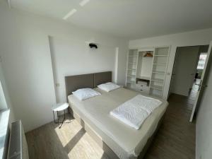 um quarto com uma cama grande e lençóis brancos em Caroline Chérie em Middelkerke