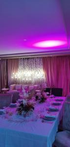 una mesa larga con iluminación rosa y techos púrpuras en AMWAJ HOTEL en El Jadida