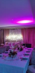 un lungo tavolo con illuminazione rosa e soffitti viola di AMWAJ HOTEL a El Jadida