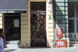 um edifício com uma porta castanha com graffiti em Red Apartment em Sarajevo
