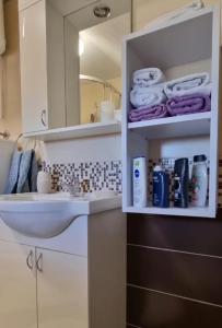 een badkamer met een wastafel, een spiegel en handdoeken bij Apartman Avram in Kotor-Varoš