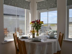 a dining table with a vase of flowers on it at Kilbride Cottage in Pollachar
