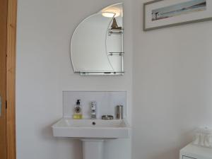 a bathroom with a sink and a mirror at Kilbride Cottage in Pollachar