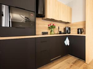 a kitchen with black cabinets and a microwave at Alexis apartament Dziwnów in Dziwnów