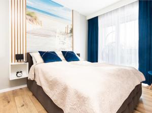 a bedroom with a large bed with blue curtains at Alexis apartament Dziwnów in Dziwnów +53 photos