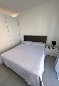 ein Schlafzimmer mit einem weißen Bett und einer Lampe in der Unterkunft Casa al mare in Cogoleto