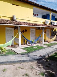 un edificio amarillo con una hamaca al aire libre en Ecomar Pousada, en São José da Coroa Grande