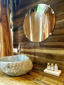 La salle de bains est pourvue d'un lavabo en pierre et d'un miroir. dans l'établissement Buena Onda Bungalows, à Santa Teresa