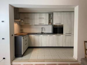 eine Küche mit weißen Schränken und Küchengeräten aus Edelstahl in der Unterkunft Appartamento a Rovereto in Rovereto