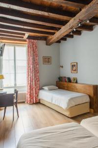 a bedroom with two beds and a desk and a window at Le Relais Des Templiers in Beaugency