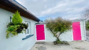 two red doors on the side of a building at Oranuisce Thatch Cottage Ballyvaughan in Ballyvaughan