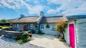 a small cottage with a red garage at Oranuisce Thatch Cottage Ballyvaughan in Ballyvaughan