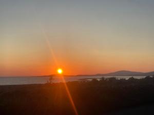 a sunset over the water with the sun in the sky at Oranuisce Thatch Cottage Ballyvaughan in Ballyvaughan