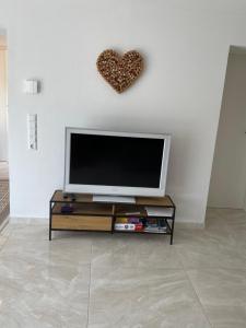 a living room with a tv and a heart on the wall at Olive in Uhldingen-Mühlhofen