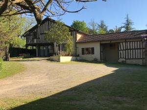 uma casa com uma árvore e uma estrada de terra em Maison Lacourrège em Urgosse