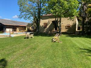 a yard with two chairs in front of a house at Maison Lacourrège in Urgosse