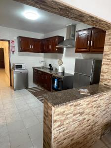 una cocina con armarios de madera y electrodomésticos de acero inoxidable en Alojamento Amor de Mãe en São Teotónio