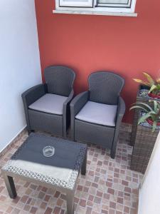 two chairs and a table in front of a wall at Alojamento Amor de Mãe in São Teotónio