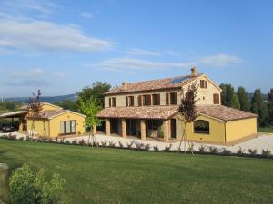 a large yellow house with a green lawn at Agriturismo La Vecchia Fonte in Castelbellino