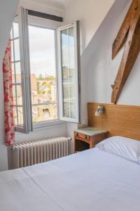 ein Schlafzimmer mit einem weißen Bett und einem Fenster in der Unterkunft Le Relais Des Templiers in Beaugency