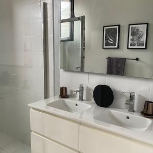 a white bathroom with a sink and a mirror at Kaz à Saint-Jacques in Anse-Bertrand
