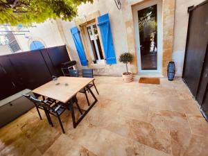 patio z drewnianym stołem i krzesłami przed budynkiem w obiekcie Le mas des glycines w mieście Salon-de-Provence +18 zdjęć