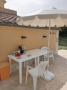 - une table et une chaise blanches avec un parasol sur la terrasse dans l'établissement Abruzzo - Teramo tra Mare e Monti con piscina, à Teramo