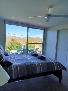 a bedroom with a bed and a large window at Snowhaven in Jindabyne