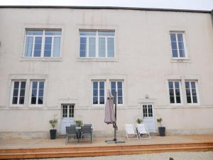 a patio with an umbrella and chairs in front of a building at Clos de la Providence Chambres d'hôtes, piscine et Spa in Nolay