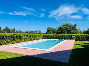 a swimming pool in a yard next to a hedge at Chalé Davim com piscina -Tranquilidade e conforto in Louriçal