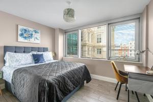 a bedroom with a bed and a desk and windows at Airhost's Brighton's Best Green Diamond Escape with Sea Views in Brighton & Hove