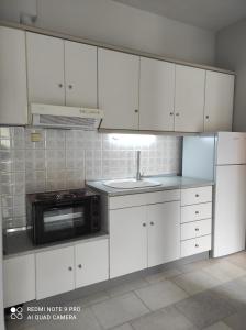 a kitchen with white cabinets and a sink and a microwave at Iris House in Ierissos