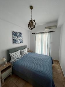 a bedroom with a blue bed and a window at Notos Sea Front Apartment in Glossa