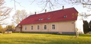 una casa vieja con techo rojo en un campo en Pärnu-Jaagupi pastoraat, en Pärnu-Jaagupi