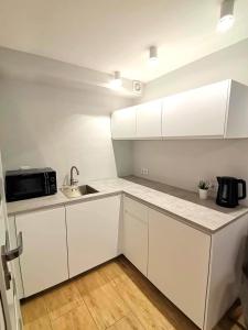 a white kitchen with a sink and a microwave at Apartament Joanna in Międzyzdroje