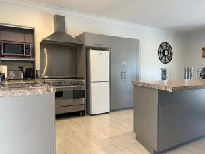 a kitchen with stainless steel appliances and a white refrigerator at A Cut Above - The Gateway to the Bay of Islands in Kerikeri