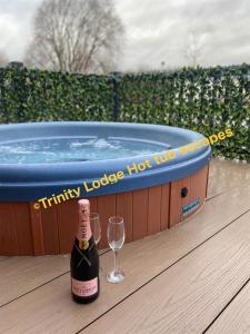 uma garrafa de champanhe e um copo ao lado de uma banheira de hidromassagem em Trinity lodge hot tub escapes at Tattershall lakes em Tattershall