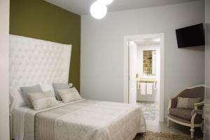 a bedroom with a white bed and a chair at CASA DA LABORA in Villanueva de Arosa