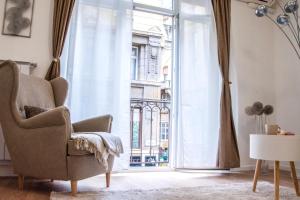 uma sala de estar com uma cadeira e uma grande janela em Asboth Downtown Apartment em Budapeste