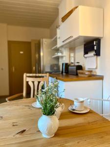 een houten tafel met twee kopjes en een vaas met bloemen erop bij Ferienwohnung Schmidtalien in Dommitzsch +16 foto's
