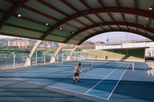 un uomo che gioca a tennis su un campo da tennis di Súper apartamento Santiago a Santiago de Compostela