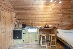 a small kitchen in a wooden cabin with two stools at Nyth Y Goedwig in Dolgellau